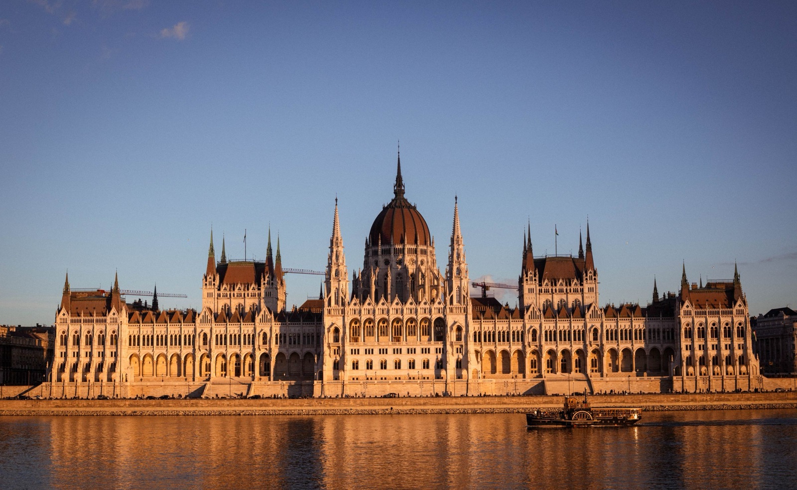 A parliament building on the river at golden hour, mirrored in still water