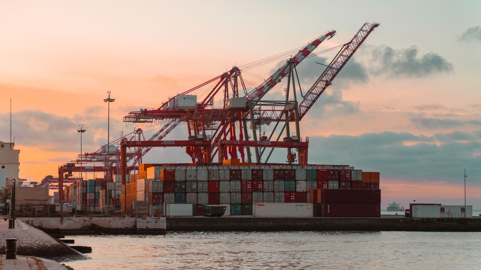 Container cranes over a working port terminal at sunset